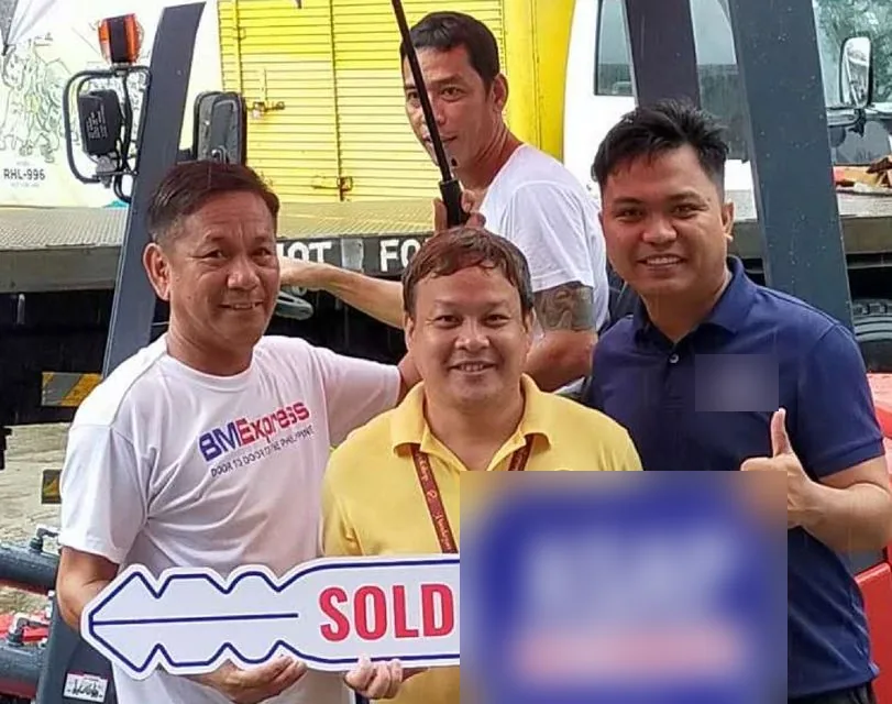 Customers and Vladimir holding the sold key at a forklift turnover in the rain