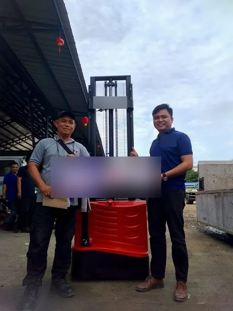 A customer and Vladimir with the sold key in front of a pallet stacker