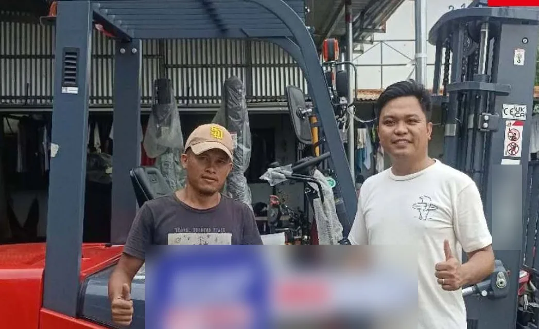 A customer and Vladimir with the sold key beside a new forklift